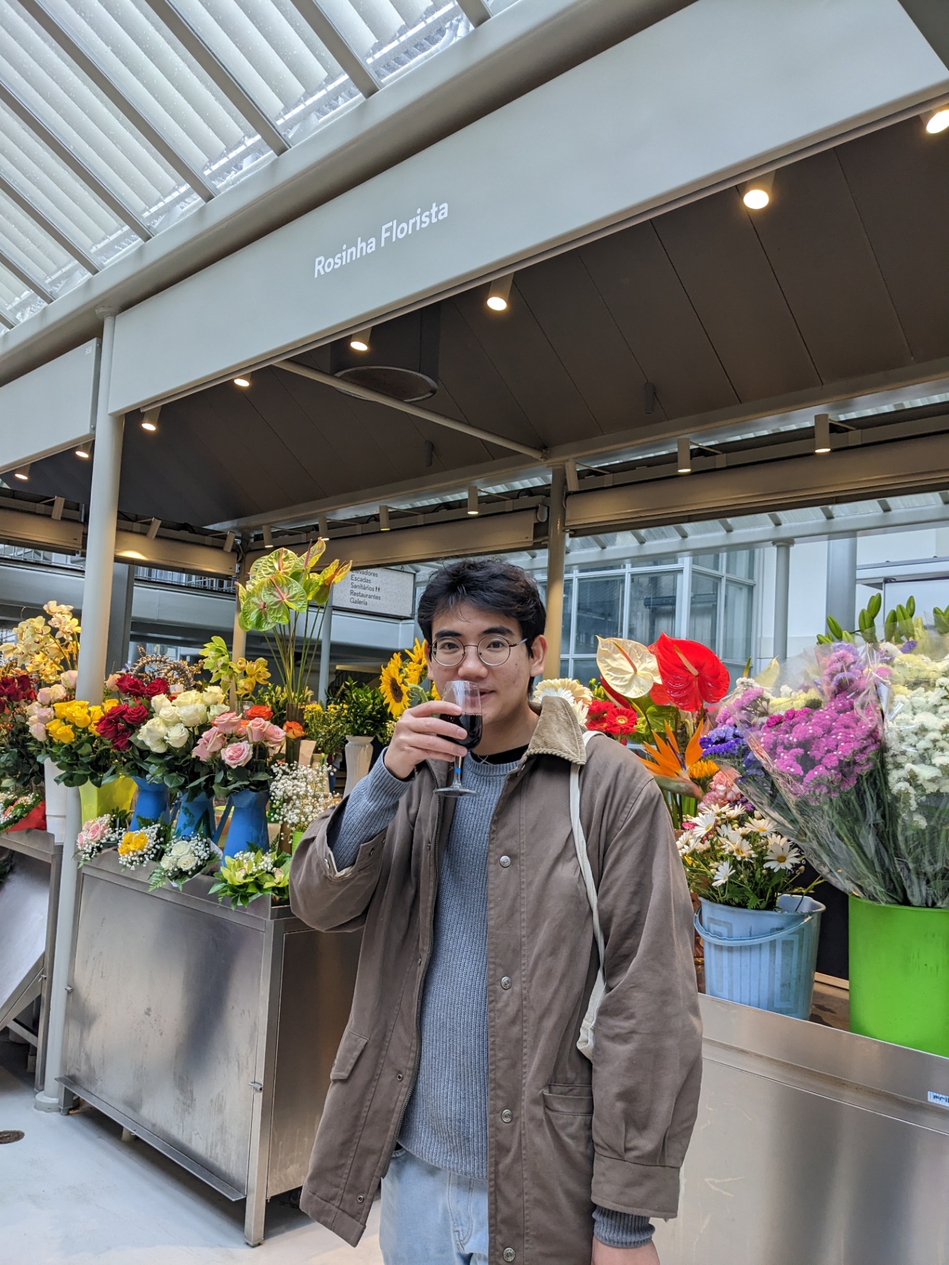 Mat sipping wine in front of a flower stall